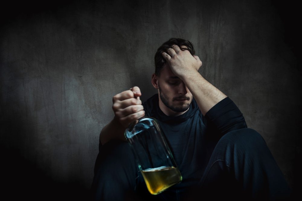 A depressed man struggling with alcoholism. Wellbrook Recovery offers tips on supporting and helping an addict