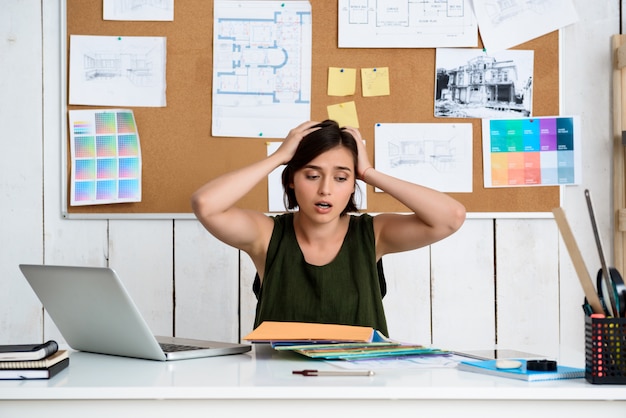 Free photo upset young beautiful businesswoman sitting at workplace