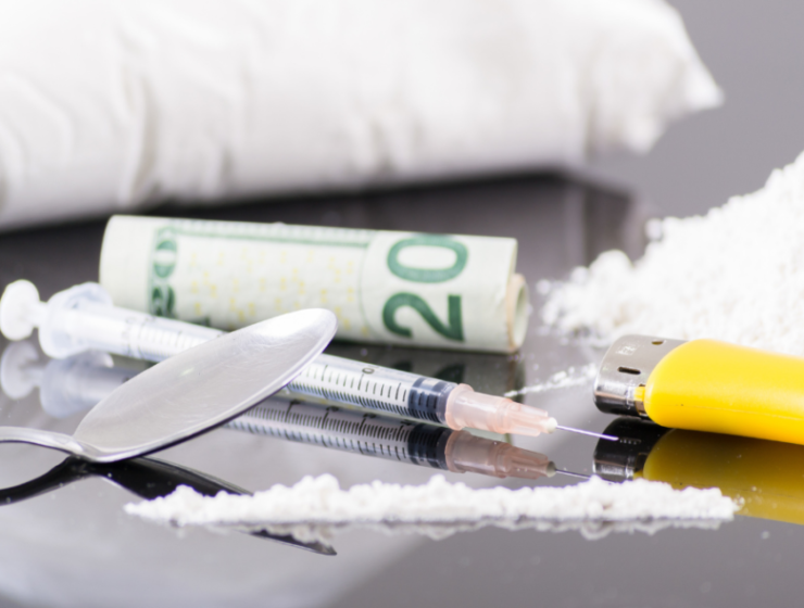 Heroin, syringes, and drug paraphernalia on a table represent addiction's grip and the pain of withdrawal.