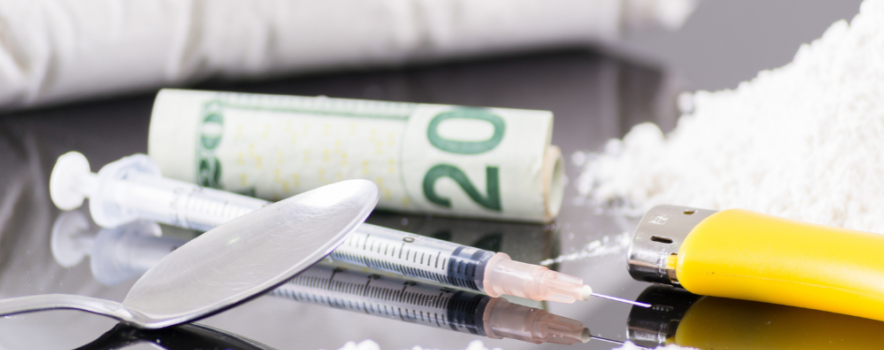 Heroin, syringes, and drug paraphernalia on a table represent addiction's grip and the pain of withdrawal.