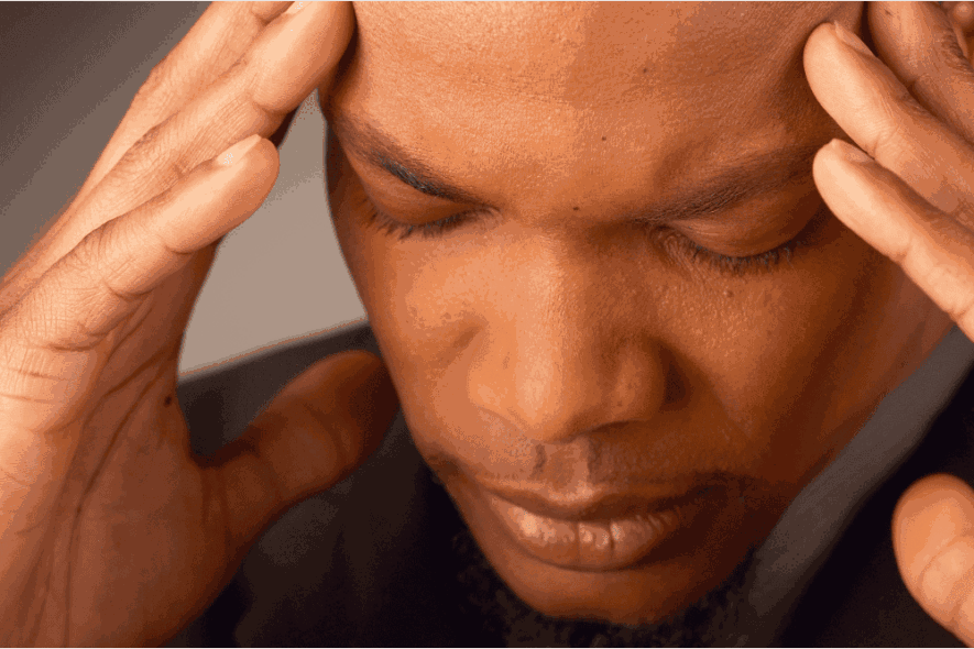 Man holding his hands to his head as he experiences an Adderall withdrawal headache.