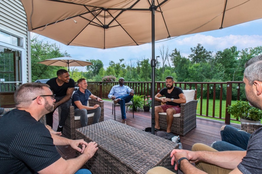 A group of men sitting on the deck at Wellbrook Recovery, engaging in group therapy.