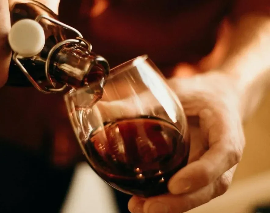 Person pouring wine into a glass, confronting the question “Can you detox from alcohol at home?”