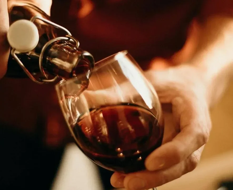 Person pouring wine into a glass, confronting the question “Can you detox from alcohol at home?”