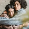 image of two women hugging, illustrating the support REBT for addiction provides to individuals in recovery.