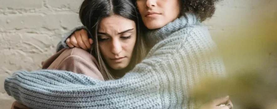 image of two women hugging, illustrating the support REBT for addiction provides to individuals in recovery.