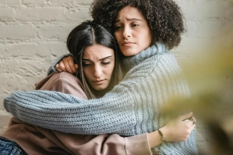 image of two women hugging, illustrating the support REBT for addiction provides to individuals in recovery.