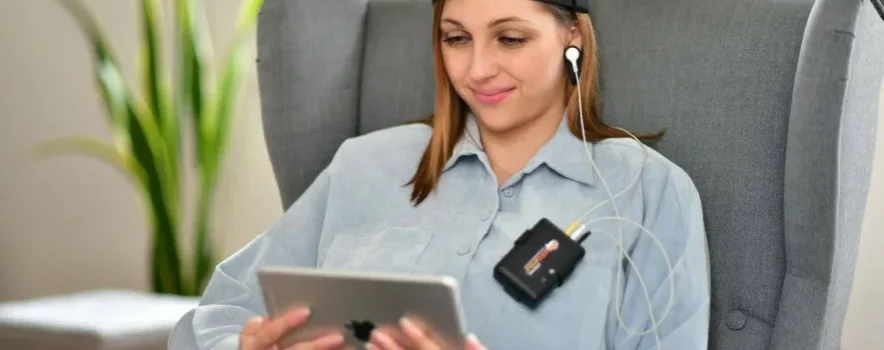 Woman receiving neurofeedback therapy for addiction recovery, wearing sensors while monitoring brain activity on a tablet