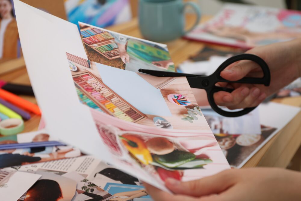 Person creating a vision board during an art therapy session by cutting images from magazines.