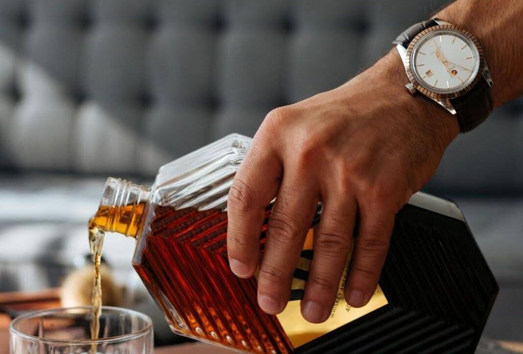 Man pouring whisky into a glass, illustrating signs of alcohol addiction