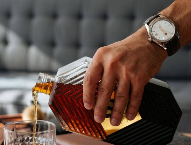 Man pouring whisky into a glass, illustrating signs of alcohol addiction