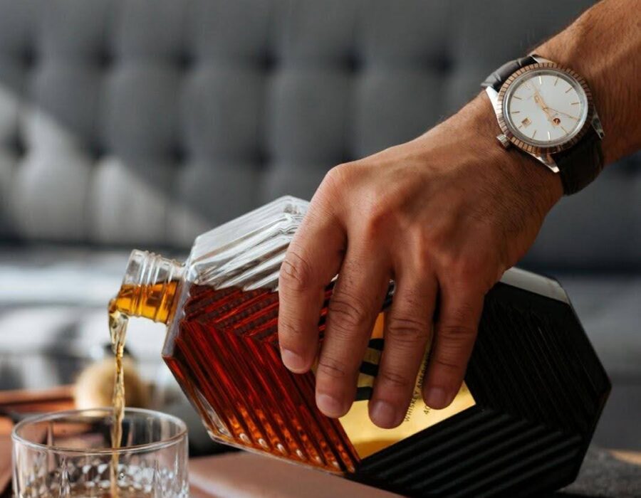 Man pouring whisky into a glass, illustrating signs of alcohol addiction