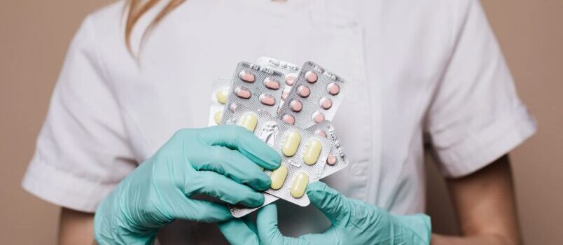 Healthcare professional holding packs of prescription medication, representing detox medications used in drug and alcohol treatment.