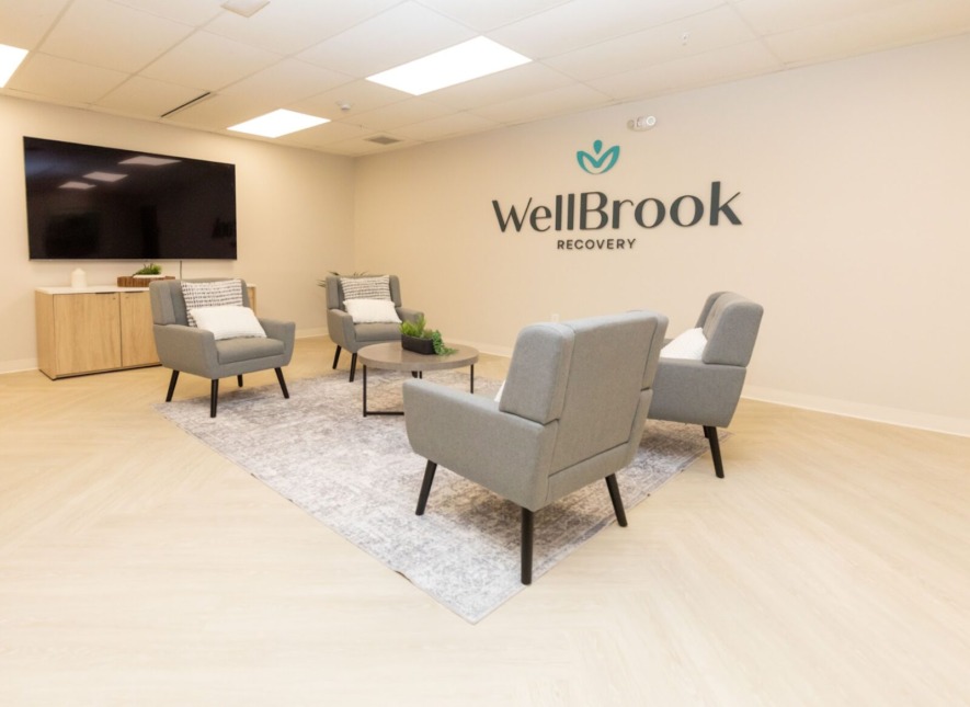 Modern group therapy room at WellBrook Recovery's rehab center in Wisconsin, featuring their logo.