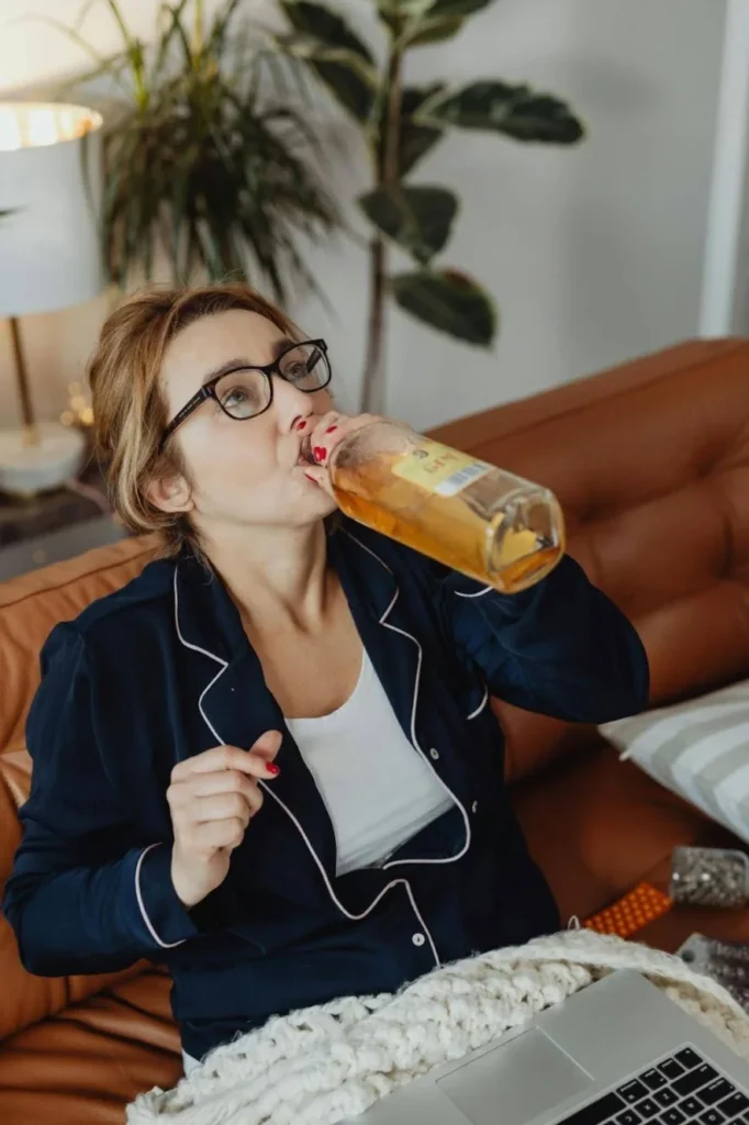 Woman sitting alone drinking alcohol, showing early signs of a drinking problem