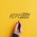 hand crossing out "less" and making it say "hope" instead of "hopeless"
