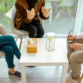 Couple sitting with psychologist during the mental therapy, cropped image with no face