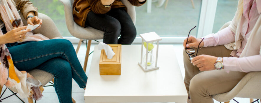 Couple sitting with psychologist during the mental therapy, cropped image with no face